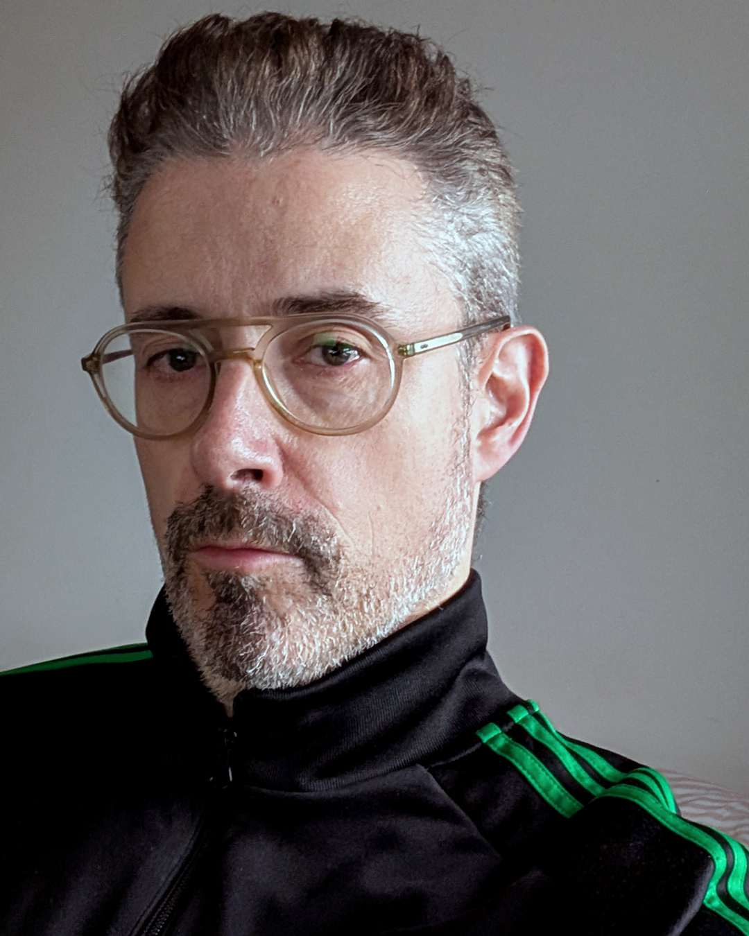 Portrait of Gerard McDonagh, the artist behind Bravespears, wearing glasses and a black jacket with green stripes.